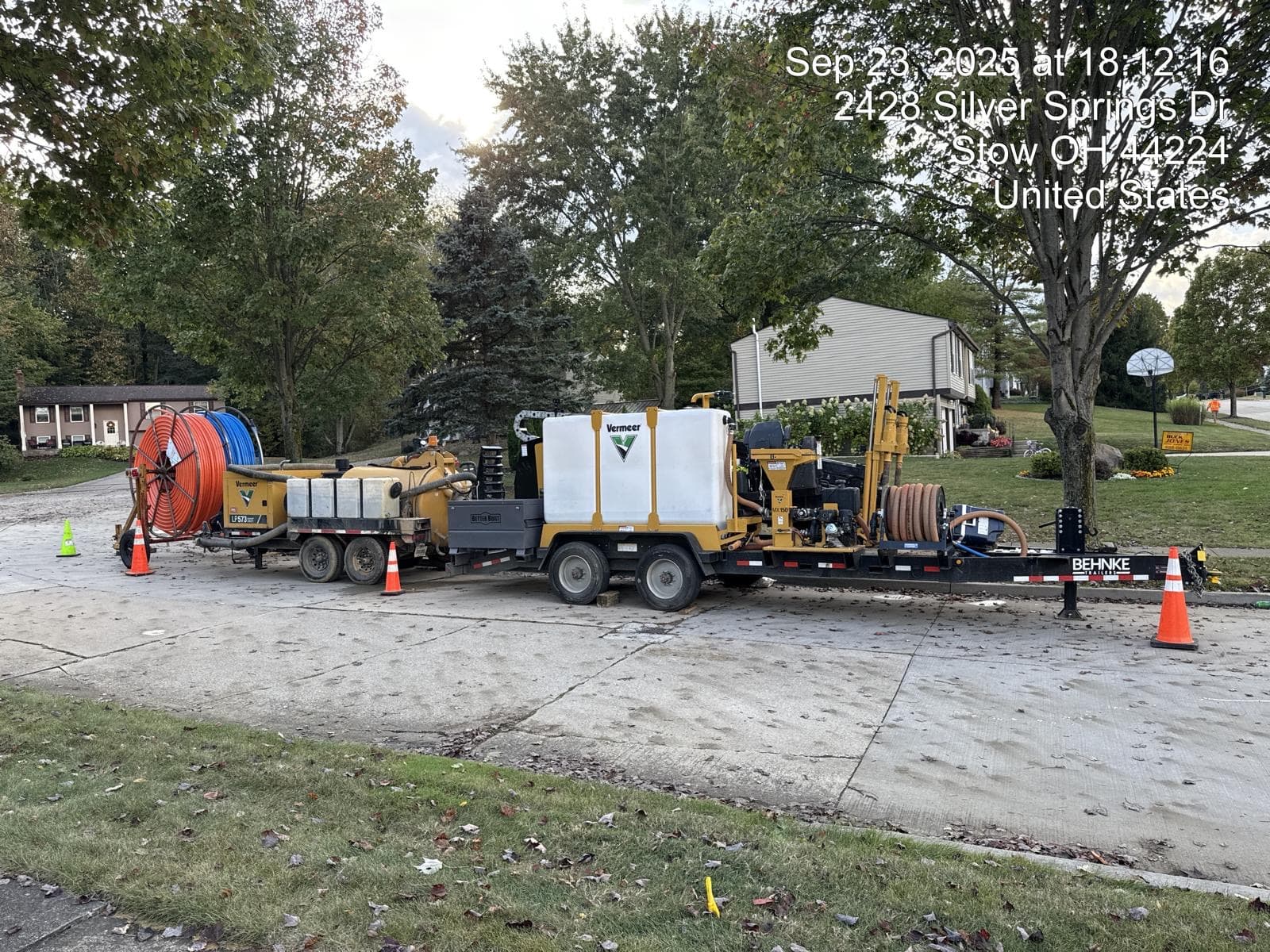 Drill rig, mud mixer, vacuum trailer and orange and blue conduit reels staged on a Stow, Ohio street